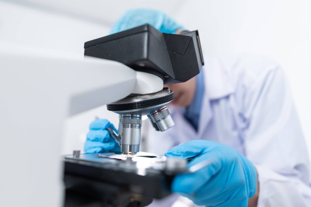 A pediatric cancer researcher examining samples under a microscope